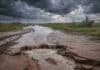 Crece el conflicto por la tasa vial: productores van a la Justicia por el destino de los fondos Camino rural colapsado tras lluvias extremas, con profundo socavón y agua desbordada bajo tormenta, reflejando la crisis vial que golpea al campo argentino