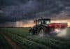 Se intensifica la crisis por la guerra: más del 50% de los alimentos podría verse afectado por la falta de fertilizantes Tractor fertilizador aplicando insumos en un cultivo bajo cielo tormentoso, reflejando el impacto de la disponibilidad de fertilizantes en la producción agrícola