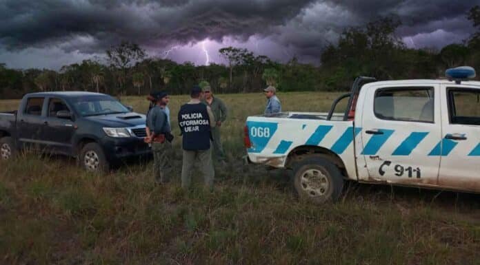 Efectivos policiales y productores rurales junto a camionetas en un campo de Formosa bajo cielo tormentoso, en un contexto de tensión durante una reunión privada