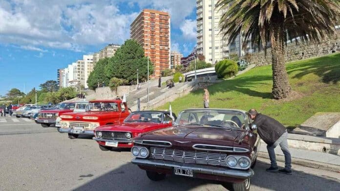 Autos clásicos estacionados en paseo costero urbano con edificios y espacio verde en Mar del Plata