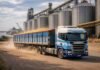 Fuerte suba en el flete: llevar granos al puerto cuesta 13,6% más y presiona al agro Camión Scania transportando granos en el puerto de Rosario con silos de almacenamiento de fondo, reflejando el impacto del costo logístico en el agro argentino