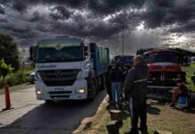 Piquetes en Quequén: el agro estalla y advierte pérdidas por US$450 millones sin liquidar Camiones detenidos en una ruta rural con personas al costado bajo cielo de tormenta en una zona productiva de Argentina
