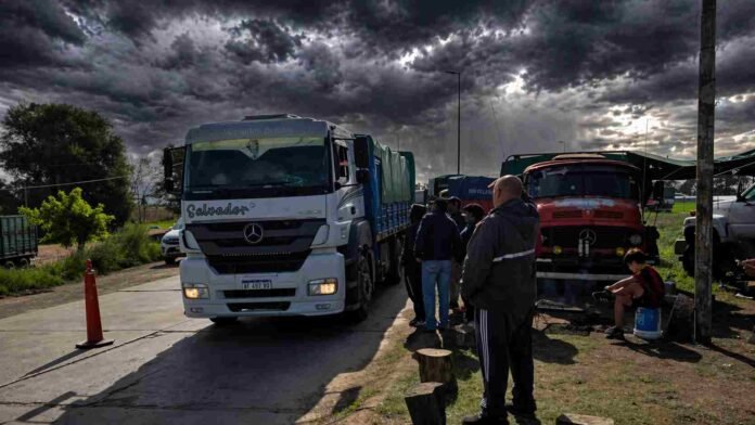 Camiones detenidos en una ruta rural con personas al costado bajo cielo de tormenta en una zona productiva de Argentina