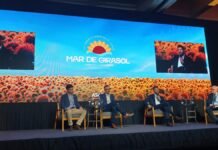 El girasol gana protagonismo global: Bunge refuerza su apuesta y ya certifica más de 84.000 hectáreas en Argentina Panel sobre comercio global del girasol en el Congreso Argentino de Girasol en Mar del Plata, con expositores en escenario y pantalla con campo de girasoles de fondo.
