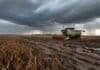 Nuevo pulso de lluvias y tormentas entre el 1 y 3 de mayo: vuelve a frenarse la cosecha Cosechadora Claas trabajando en un lote de soja madura con barro y huellas profundas, avanzando en el mismo sentido de los surcos bajo cielo de tormenta con lluvias en el horizonte.