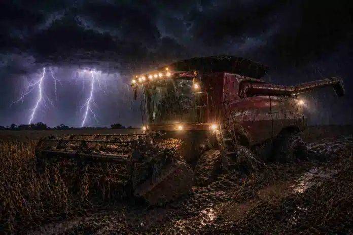 Cosechadora encajada en el barro durante tormenta con relámpagos en campo de soja por lluvias intensas