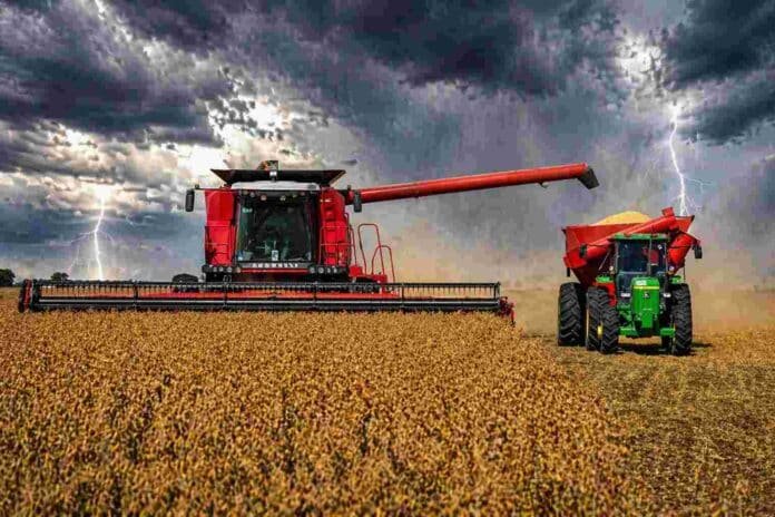 Cosechadora y tractor trabajando en la cosecha de soja bajo cielo de tormenta con relámpagos en la zona núcleo argentina