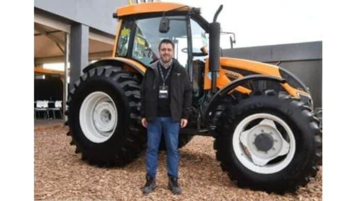 Ejecutivo del sector agro posando frente a un tractor agrícola de gran porte en una exposición de maquinaria en Argentina