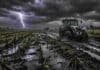 Golpean lluvias de hasta 70 mm y ráfagas de 70 km/h en Buenos Aires Campo agrícola en Buenos Aires bajo lluvias intensas, con suelo anegado y barro, un tractor circulando por camino rural deteriorado y un relámpago en el cielo, reflejando el impacto climático en el agro.