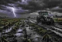 Golpean lluvias de hasta 70 mm y ráfagas de 70 km/h en Buenos Aires Campo agrícola en Buenos Aires bajo lluvias intensas, con suelo anegado y barro, un tractor circulando por camino rural deteriorado y un relámpago en el cielo, reflejando el impacto climático en el agro.