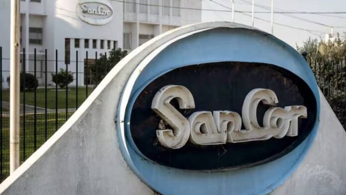 Cartel de SanCor en planta industrial con edificio de la cooperativa láctea al fondo en contexto de crisis