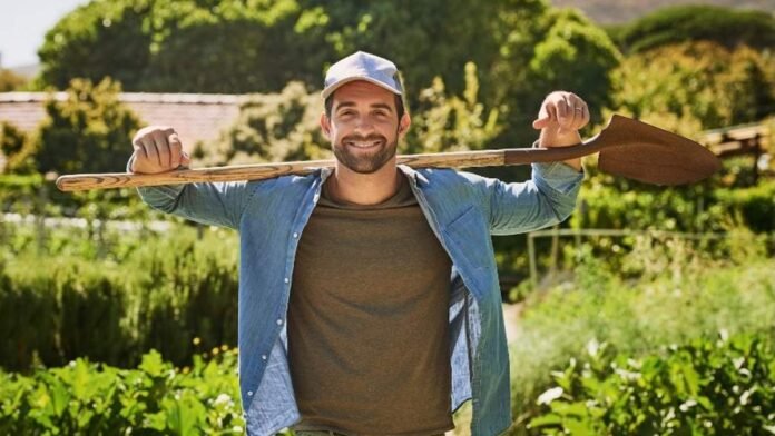 Productor joven en campo agrícola con herramientas reflejando innovación y trabajo en el agro