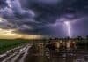 Pronóstico: lluvias, tormentas aisladas y viento en 14 provincias y condiciones irregulares en el campo Campo ganadero con camino rural embarrado y vacunos bajo cielo tormentoso con relámpago, reflejando condiciones climáticas inestables en el agro argentino