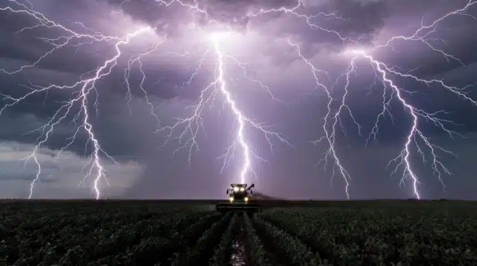 tormentas-severas-100mm-campo-argentino-ruralnet Tormenta severa con lluvias intensas y relámpagos sobre un campo agrícola argentino con cultivo de soja y tractor trabajando bajo condiciones climáticas adversas