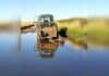 Se dispara el reclamo en el agro: tras inundaciones, productores exigen obras urgentes y denuncian abandono Tractor detenido en un camino rural completamente inundado, con agua cubriendo la traza y reflejando la crisis hídrica que afecta a zonas productivas de Buenos Aires.