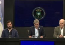 El Gobierno reveló el cronograma completo de baja de retenciones hasta 2028: qué le espera a la soja, el maíz, el girasol y el sorgo Funcionarios argentinos brindan una conferencia de prensa en el Ministerio de Economía. Tres hombres sentados frente a micrófonos aparecen bajo el escudo oficial de la República Argentina, con una bandera argentina al costado, en una imagen institucional de formato panorámico.