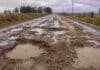 Más de 20 proyectos clave para el campo siguen frenados en la Legislatura bonaerense Camino rural en muy mal estado con barro, pozos profundos y charcos de agua, rodeado de campos y alambrados bajo un cielo nublado.