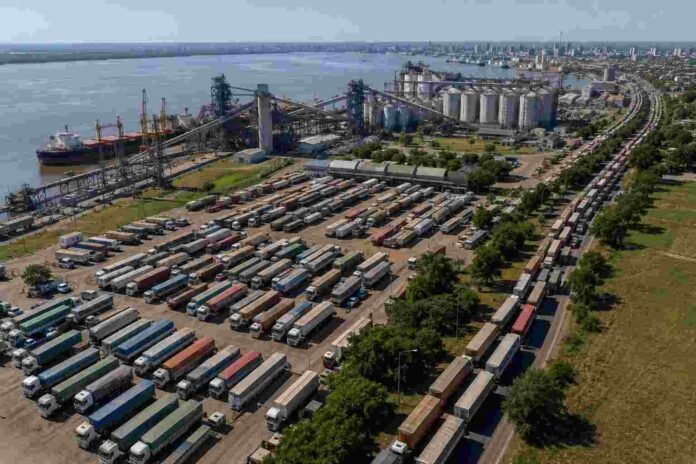 Vista aérea del puerto de Rosario con un playón lleno de camiones cerealeros y una extensa fila de vehículos esperando ingresar para descargar granos en terminales portuarias del Gran Rosario