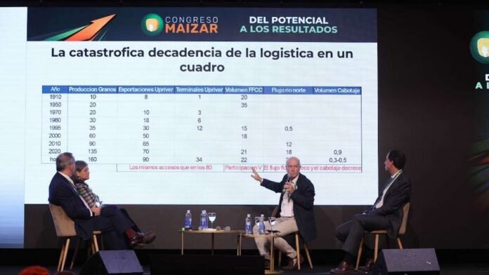 congreso-maizar-logistica-exportaciones-granos Panel de especialistas durante el Congreso Maizar analizando la evolución de la logística y el transporte de granos en Argentina, con una presentación técnica proyectada en pantalla gigante.