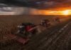 Santa Fe rumbo a una campaña agrícola récord Tres cosechadoras Massey Ferguson cosechando maíz en formación tándem durante un atardecer tormentoso en un lote con suelo mojado y barro en la región pampeana argentina
