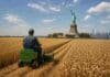 Mínima cosecha de trigo en EE.UU. desde 1972: soja y maíz también subieron en Rosario Agricultor manejando una pequeña cosechadora en un campo de trigo de Estados Unidos con la Estatua de la Libertad y el skyline de Nueva York al fondo