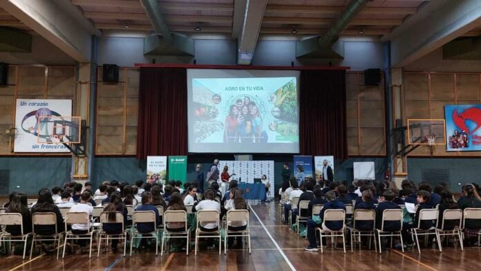 Charla educativa sobre agro con estudiantes en auditorio escolar, con presentación en pantalla y público sentado escuchando en Argentina.