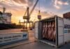 Exportaciones de carne en alza, pero con una industria condicionada por la falta de hacienda Contenedor frigorífico con carne vacuna argentina en puerto de exportación con buque de carga y grúas al fondo