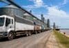 El aluvión de camiones en los puertos disparó la liquidación de divisas: en abril ingresaron 23% más dólares que en marzo Fila de camiones cargados con granos esperando descarga en puerto agroexportador argentino, con silos y barco granelero a la vera del río.