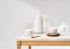 La proteína, mucho más que un nutriente clave para el mantenimiento de la masa muscular Botella y vasos de leche sobre una mesa de madera en una escena minimalista vinculada a nutrición y proteína láctea