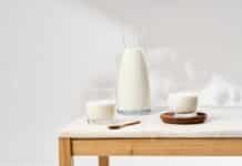 La proteína, mucho más que un nutriente clave para el mantenimiento de la masa muscular Botella y vasos de leche sobre una mesa de madera en una escena minimalista vinculada a nutrición y proteína láctea