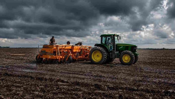 siembra-suelo-humedo-cielo-tormentoso-campo-ruralnet Tractor con sembradora trabajando sobre suelo húmedo en un campo argentino, bajo un cielo tormentoso con nubes oscuras.