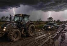 Tormentas con hasta 110 mm y ráfagas de 70 km/h impactan en 6 provincias y complican al campo Tractor Valtra embarrado tirando con una linga de una camioneta Amarok encajada en un camino rural con barro, bajo tormenta intensa con relámpagos y lluvias en el Litoral argentino.