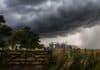 Fuerte frente de tormentas golpea al NEA: hasta 90 mm y riesgo de granizo Tormenta severa con fuertes vientos y lluvias sobre campo rural con tranquera y silos al fondo en Argentina