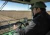 Cambia la forma en que se fijan los sueldos del campo: qué significa para los trabajadores rurales Trabajador rural operando maquinaria agrícola desde la cabina durante la cosecha, con vista al lote y al cabezal de la máquina en pleno trabajo