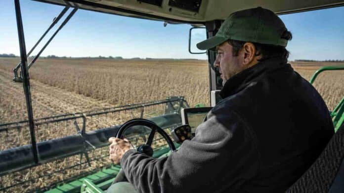 trabajador-rural-operando-maquinaria-agricola-cosecha Trabajador rural operando maquinaria agrícola desde la cabina durante la cosecha, con vista al lote y al cabezal de la máquina en pleno trabajo