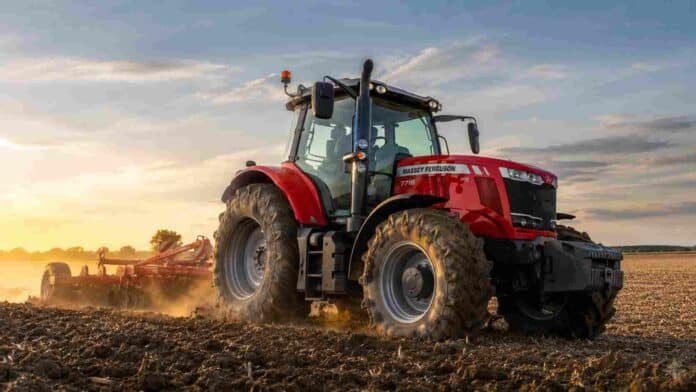 Tractor Massey Ferguson trabajando la tierra en un campo agrícola al atardecer, con polvo en suspensión y maquinaria de labranza en plena tarea rural.