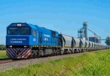 El Gobierno eximió de impuestos aduaneros a los trenes de carga para evitar un encarecimiento del 40% en las inversiones Formación del tren Belgrano Cargas con vagones cerealeros transportando granos en zona rural argentina, con silos y campos agrícolas de fondo.
