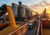 La agroindustria explica más del 70% de las exportaciones en la mitad de las provincias argentinas Puerto agroindustrial argentino al atardecer con granos cargándose en barcazas, silos, camiones y buques, representando el peso exportador de la agroindustria provincial.