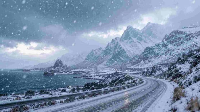 alerta-nevadas-cordillera-san-juan-tierra-fuego Ruta de montaña cubierta de nieve durante una nevada intensa, con cordillera, viento fuerte y condiciones invernales severas.
