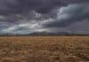 Mayo dejó lluvias escasas en la zona relevada por la Red BCCBA Campo en barbecho con rastrojo de maíz en la provincia de Córdoba, Argentina, con suelo seco, sierras al fondo y nubes negras de tormenta aproximándose