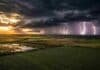 Tormentas localmente fuertes en el NEA y Misiones este viernes antes de una mejora generalizada el sábado Vista aérea de campos agrícolas del noreste argentino con cultivo de soja en primer plano, cielo de tormenta y relámpagos intensos en el horizonte al amanecer.