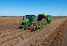 El maní va camino a una cosecha histórica: proyectan la mayor producción de la serie Tractor trabajando con arrancadora invertidora de maní en un campo argentino, con hileras de cultivo sin arrancar por delante y maní invertido sobre el suelo detrás de la maquinaria.