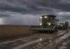 Pronóstico para los próximos 3 días en el campo: tormentas en la región núcleo y tiempo inestable en 13 provincias Cosechadora sojera con luces encendidas avanza por un camino rural embarrado con huellones y charcos junto a un lote de soja en estado R7 bajo una tormenta con lluvia y relámpagos en la región núcleo argentina.