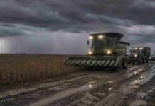 Pronóstico para los próximos 3 días en el campo: tormentas en la región núcleo y tiempo inestable en 13 provincias Cosechadora sojera con luces encendidas avanza por un camino rural embarrado con huellones y charcos junto a un lote de soja en estado R7 bajo una tormenta con lluvia y relámpagos en la región núcleo argentina.