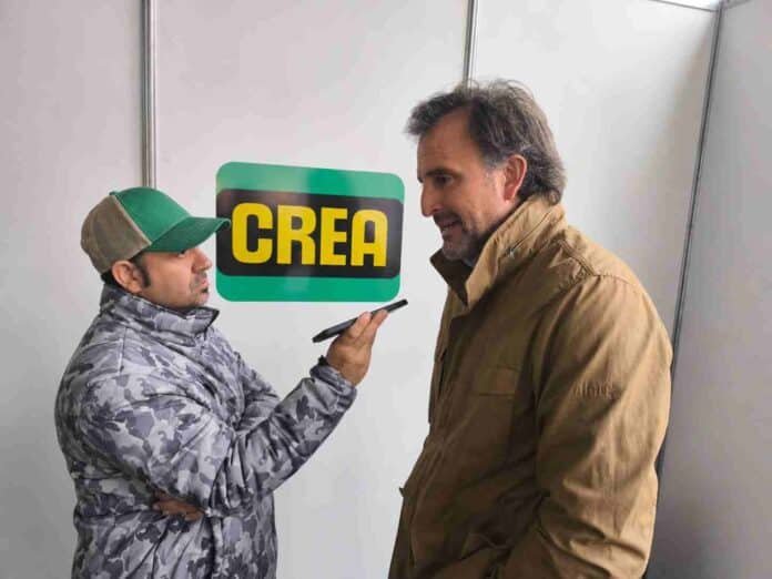 Periodista agropecuario realizando una entrevista a un referente del sector durante una jornada técnica de CREA, en un espacio institucional vinculado a la producción agropecuaria argentina