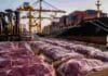 La faena bovina sube en mayo pero acumula casi un 10% menos que el año pasado Cortes de carne vacuna embalados para exportación en un puerto, con grúas, contenedores y un buque de carga al fondo.
