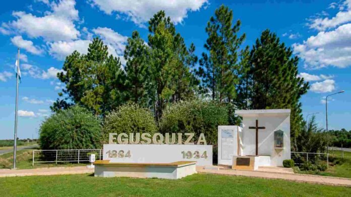 ingreso-egusquiza-cielo-despejado-ruralnet Monumento de ingreso a Egusquiza con cielo despejado, árboles verdes y entorno urbano-rural iluminado durante el día.