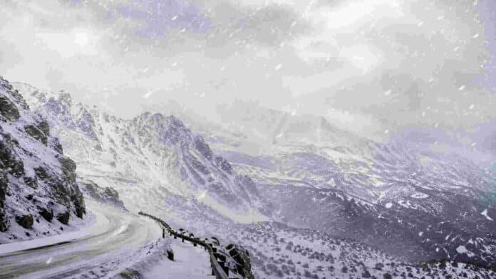 nevadas-cordillera-mendoza-neuquen-alerta Intensa nevada en una zona cordillerana de los Andes, con montañas cubiertas de nieve, viento fuerte y camino de montaña parcialmente nevado bajo condiciones invernales severas.