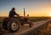 Paritaria rural 2026: cuánto cobra un peón general, un tractorista y un operador de fumigadora en junio y julio Peón rural argentino con camperón conduciendo un antiguo tractor Fiat por un camino rural al amanecer, junto a un cultivo extensivo de soja en la llanura pampeana bajo luz dorada de invierno.
