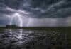 Pronóstico climático invierno 2026: más lluvia y temperaturas por encima de lo normal Tormenta eléctrica sobre un campo agrícola de la región pampeana argentina, con relámpagos ramificados, suelo anegado y cielo cubierto por nubes de tormenta. La imagen representa el pronóstico de lluvias superiores a lo normal para el invierno 2026 en la principal zona productiva del país.